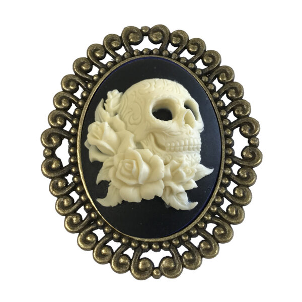 Jewelry Halloween Ivory skull with roses on a black background in an antique gold brooch setting. Setting measures 2-1/4″x 2″.